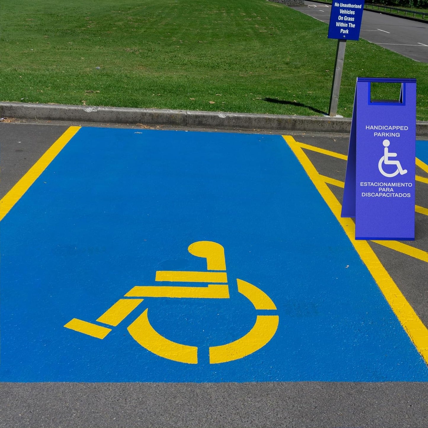 Blue accessible parking sign positioned next to painted wheelchair symbol on parking lot pavement