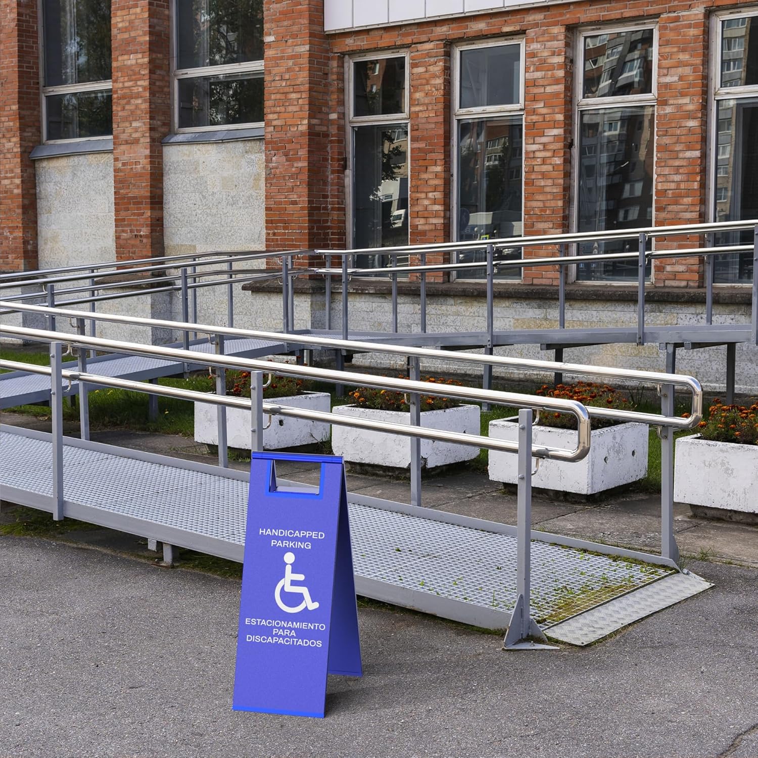 Blue handicap parking sign with wheelchair symbol positioned at commercial building accessible ramp entrance