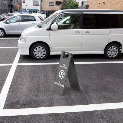 Gray no parking warning sign positioned on street next to white van for traffic control and parking enforcement.
