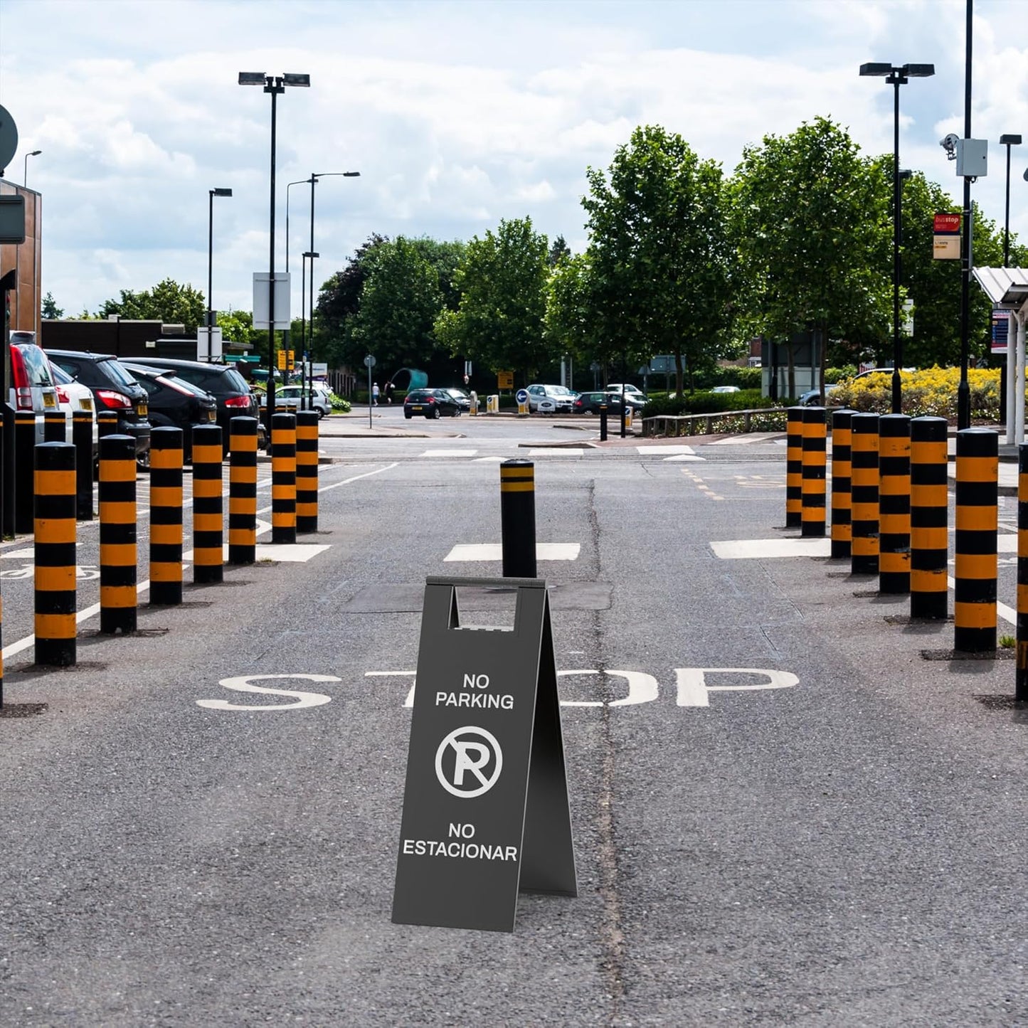 Black parking restriction sign with prohibited symbol placed in commercial parking lot with orange traffic barriers
