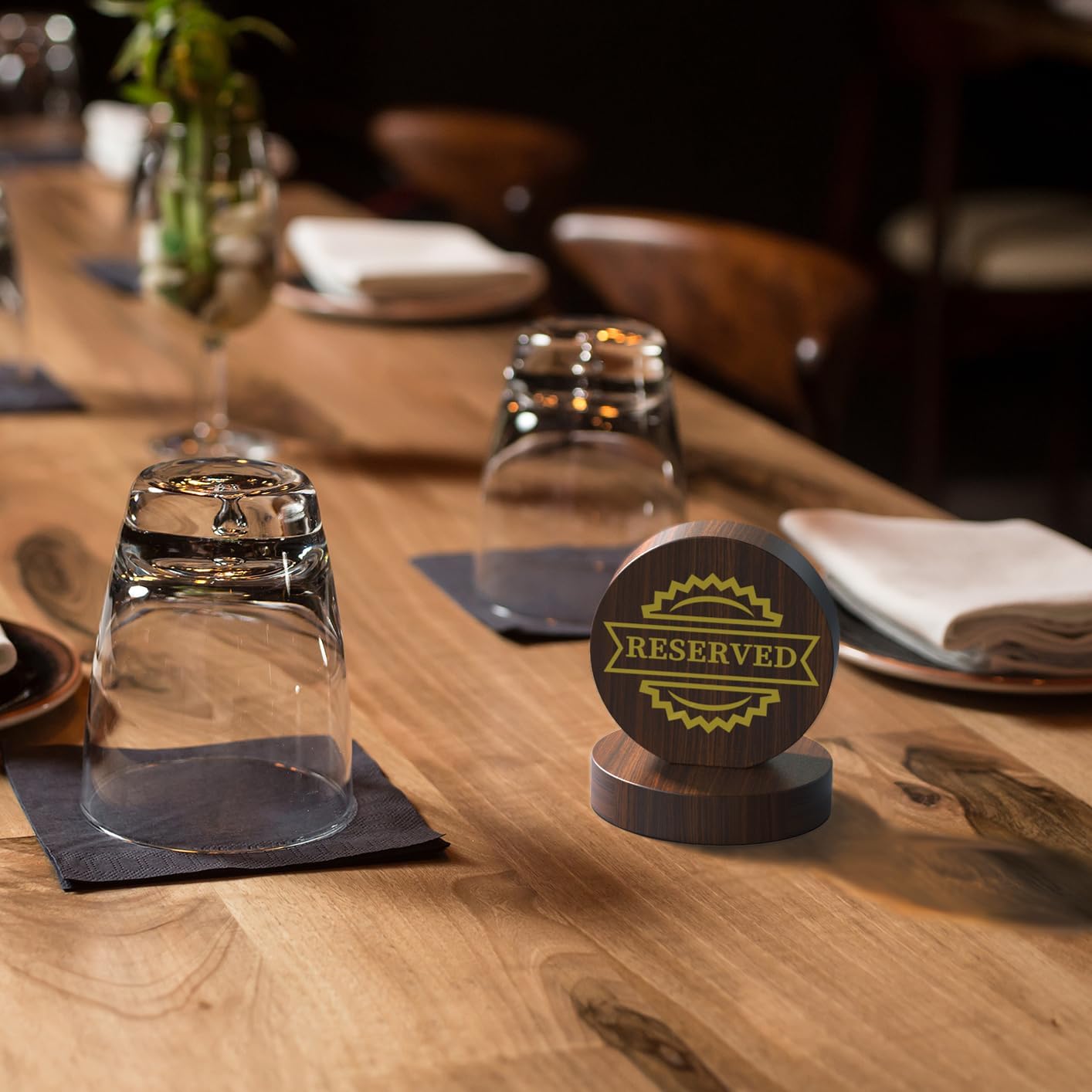 Gold engraved wooden reserved sign on formal dining table with wine glasses and elegant table setting
