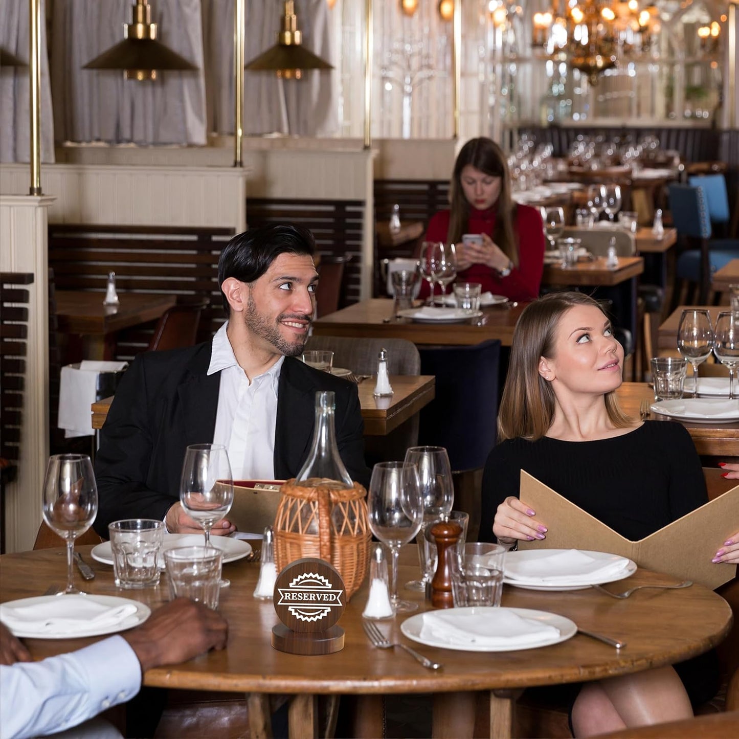 Couple dining at restaurant table with wooden reserved sign, wine service and intimate atmosphere
