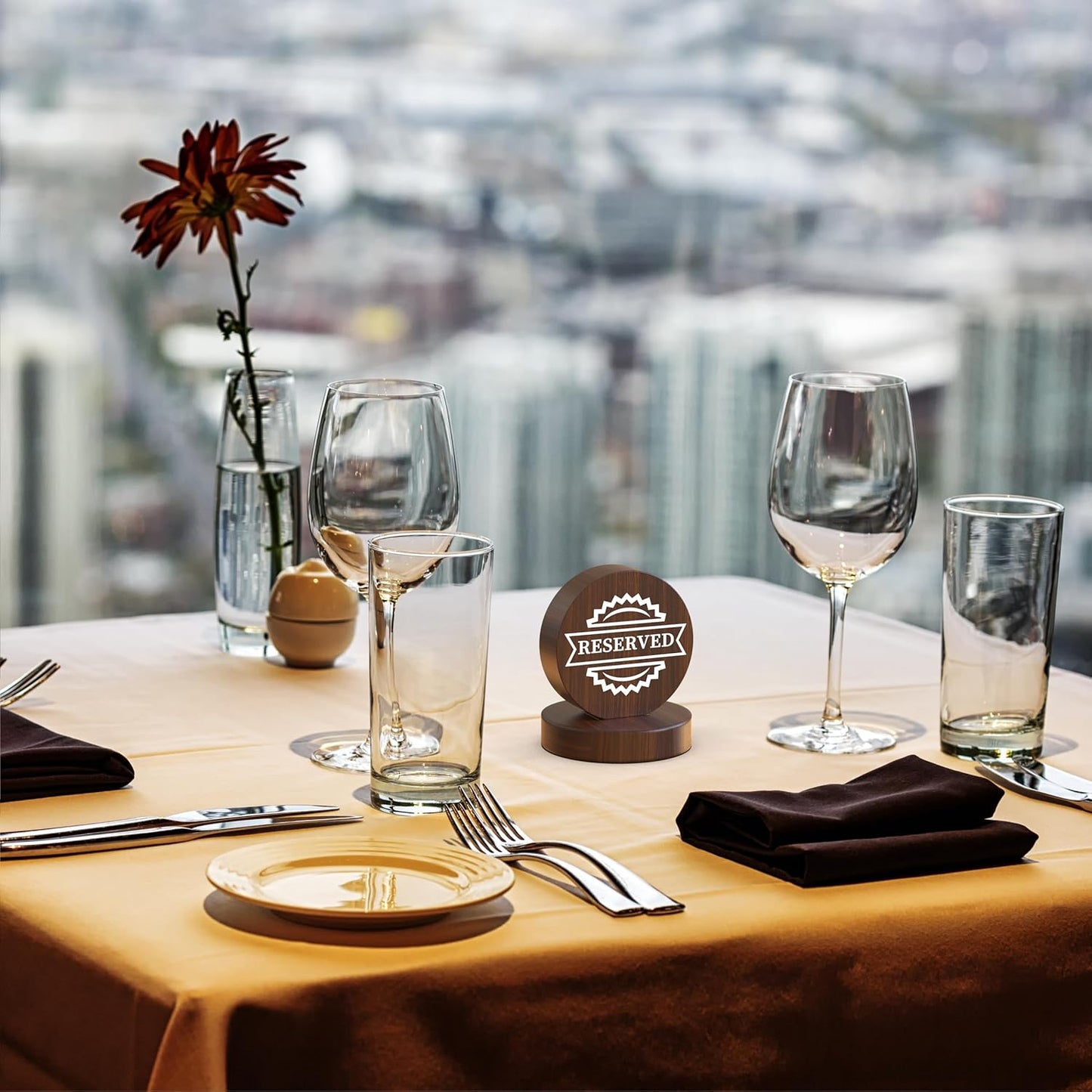 Wooden reserved table sign on restaurant table with city skyline view, wine glasses and formal place setting