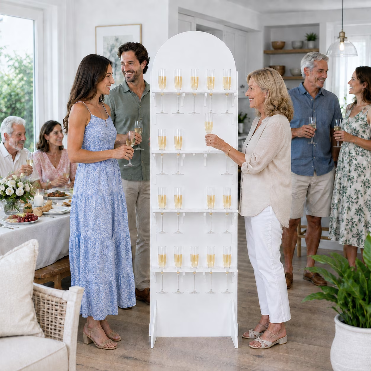 Guests serving drinks from a white 20-flute champagne wall stand at an indoor celebration