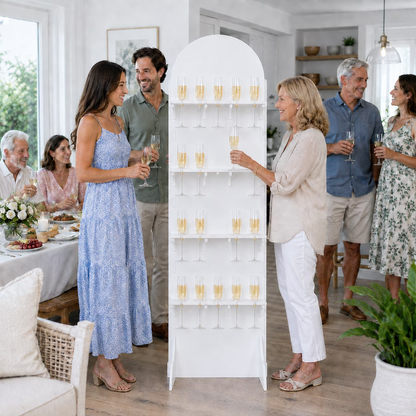 Guests serving drinks from a white 20-flute champagne wall stand at an indoor celebration